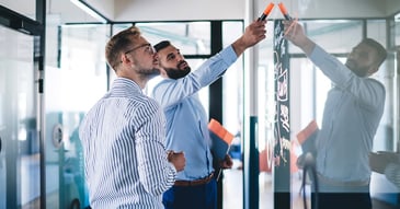 Two professionals standing at a dry-erase board.