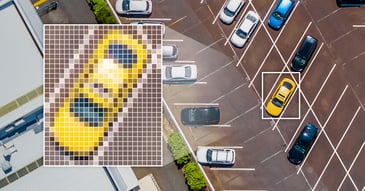 Overhead photography of cars in a parking lot; a yellow car has been selected for computer vision.