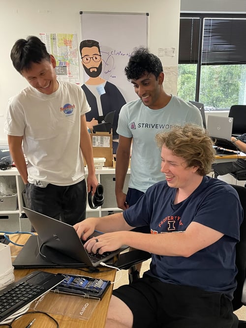 Striveworks team member shows interns something on laptop