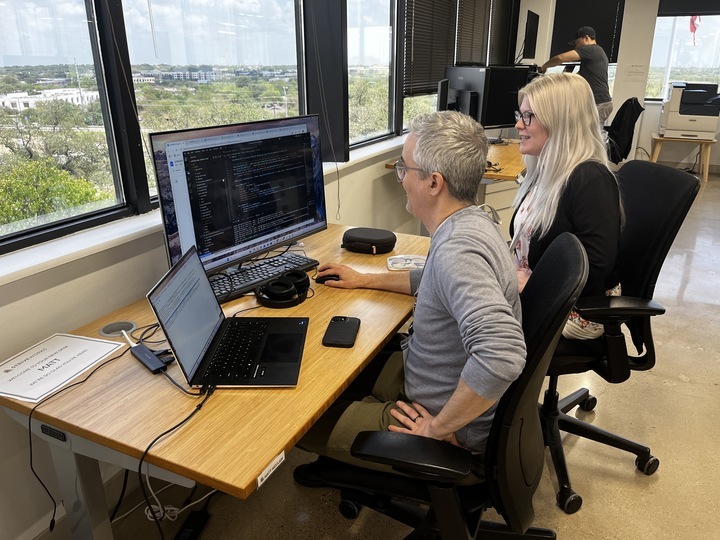 Two Striveworks team members working on a project on a single monitor.