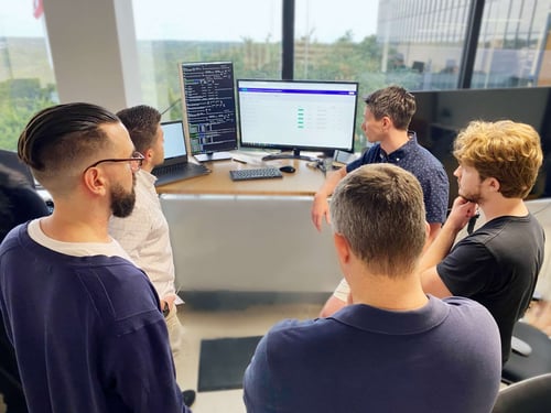 Striveworks team members review a potential solution around a computer
