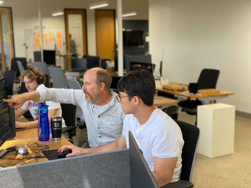 Striveworks team members exchanging ideas in front of a computer