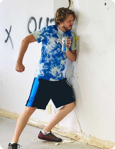 Striveworks team member busting through a wall holding a ripit drink